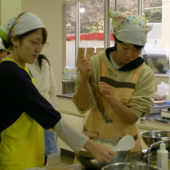 秋田の郷土料理「だまこもち」の調理を体験する渡部さん（右）